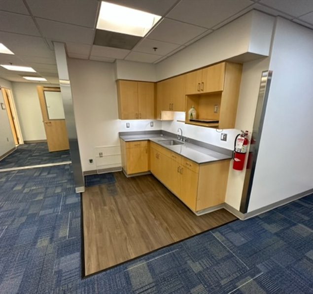 Renovated office suite with a kitchenette, wood cabinets, and new carpet.