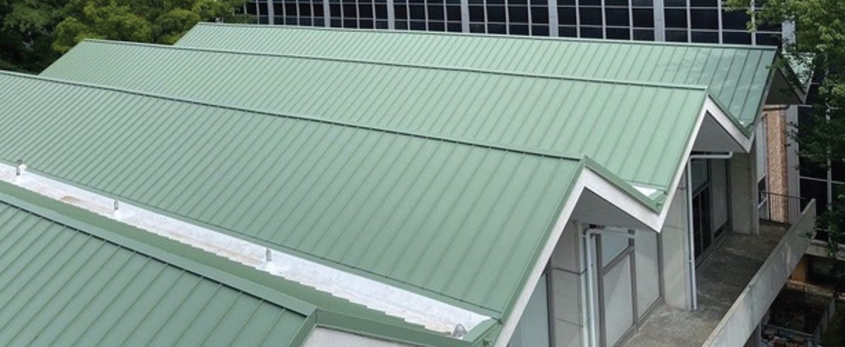 New green standing-seam metal roof on a cafeteria building.
